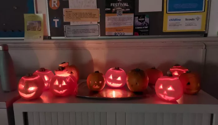 A row of carved pumpkins sat on top of a cabinet, with candles in them.