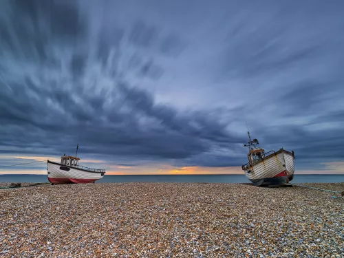 Sunrise at Dungeness with two boats on the shingle in low tide