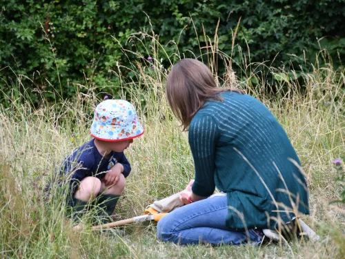 Adult with child kneeling on the grass and learning about wildlife at Nature Tots by Tim Horton