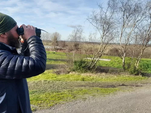 Paul Hadaway looking out at bettesehanger country park with his binoculars to his face