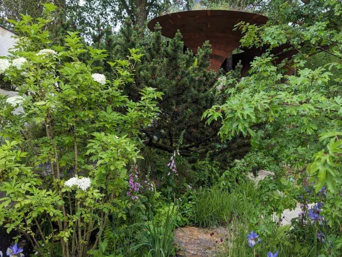 A path and metal structure amongst greenery at Chelsea Flower Show