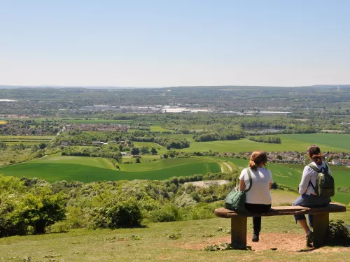 Two people sitting on a bench looking out over the views at Blue Bell Hill