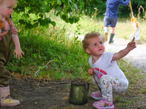 Nature tots toddler playing and looking up at parent